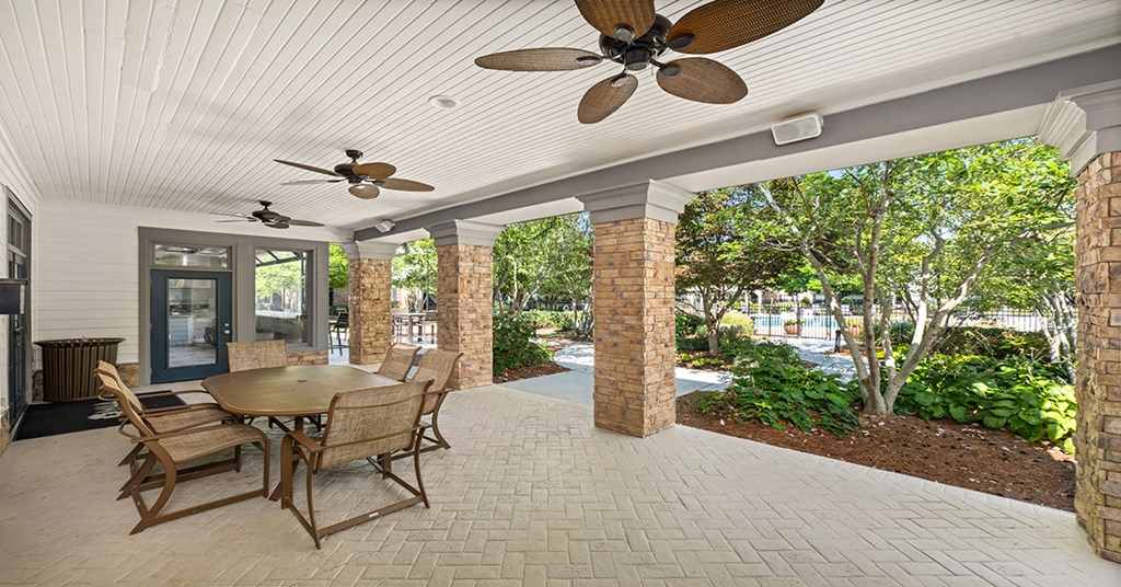 A patio with a table and chairs and a ceiling fan.