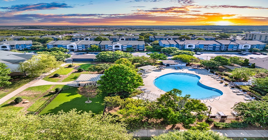 A sunset view of a resort with a swimming pool and buildings.