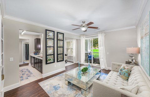 A living room with a glass coffee table and a white sofa.