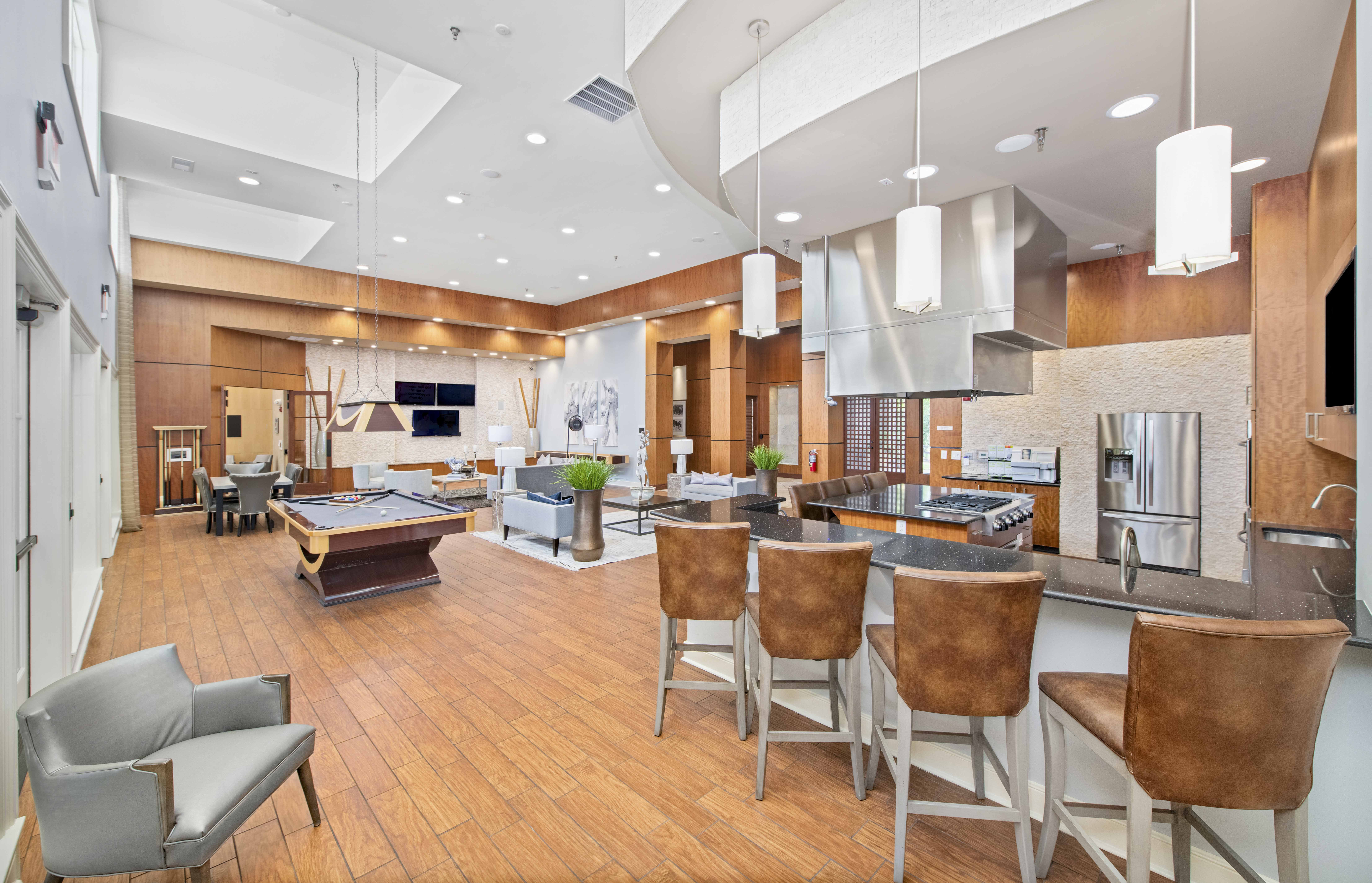 a clubhouse with a pool table and a bar with chairs