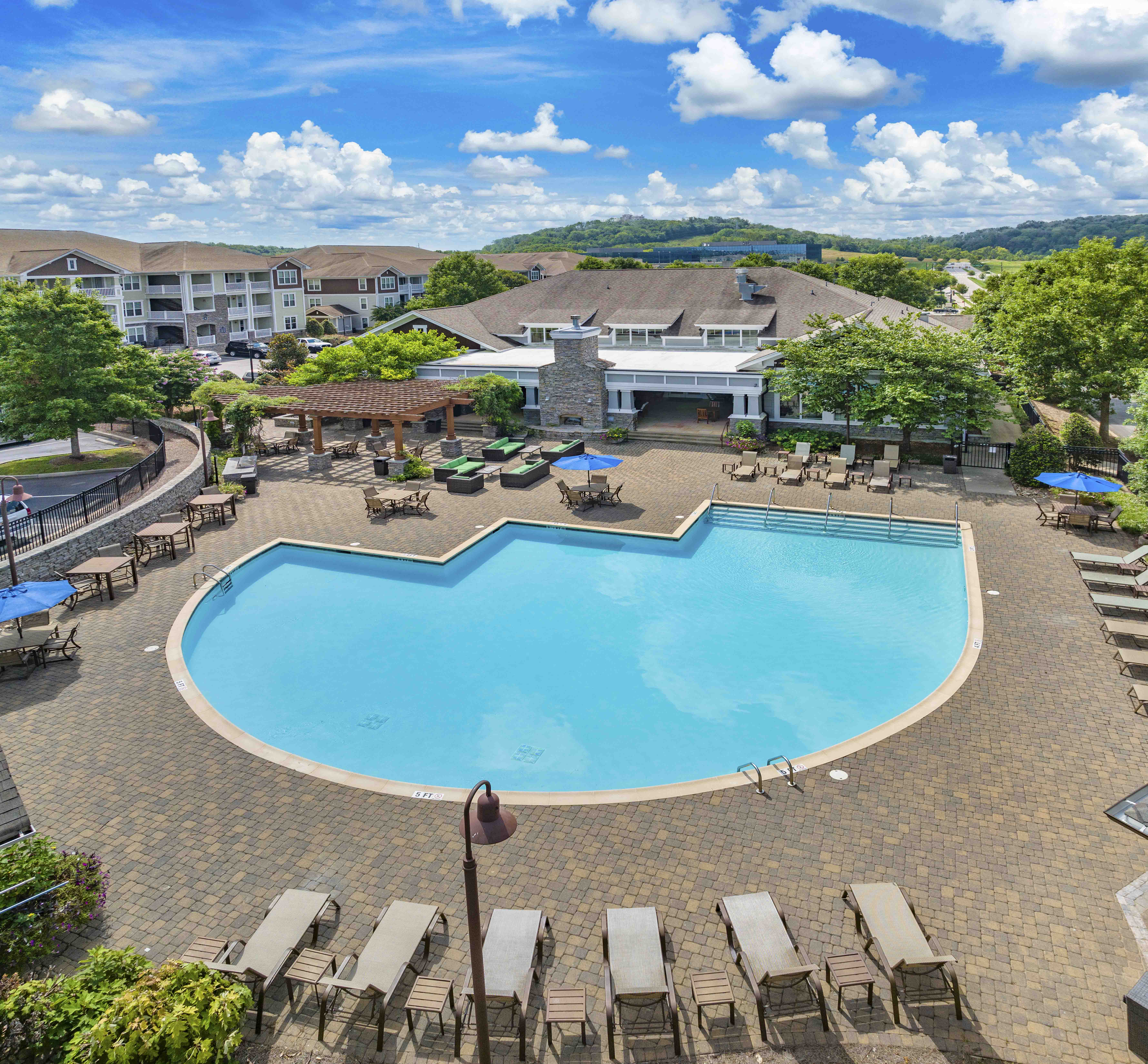 an aerial view of a resort pool with chairs and a building