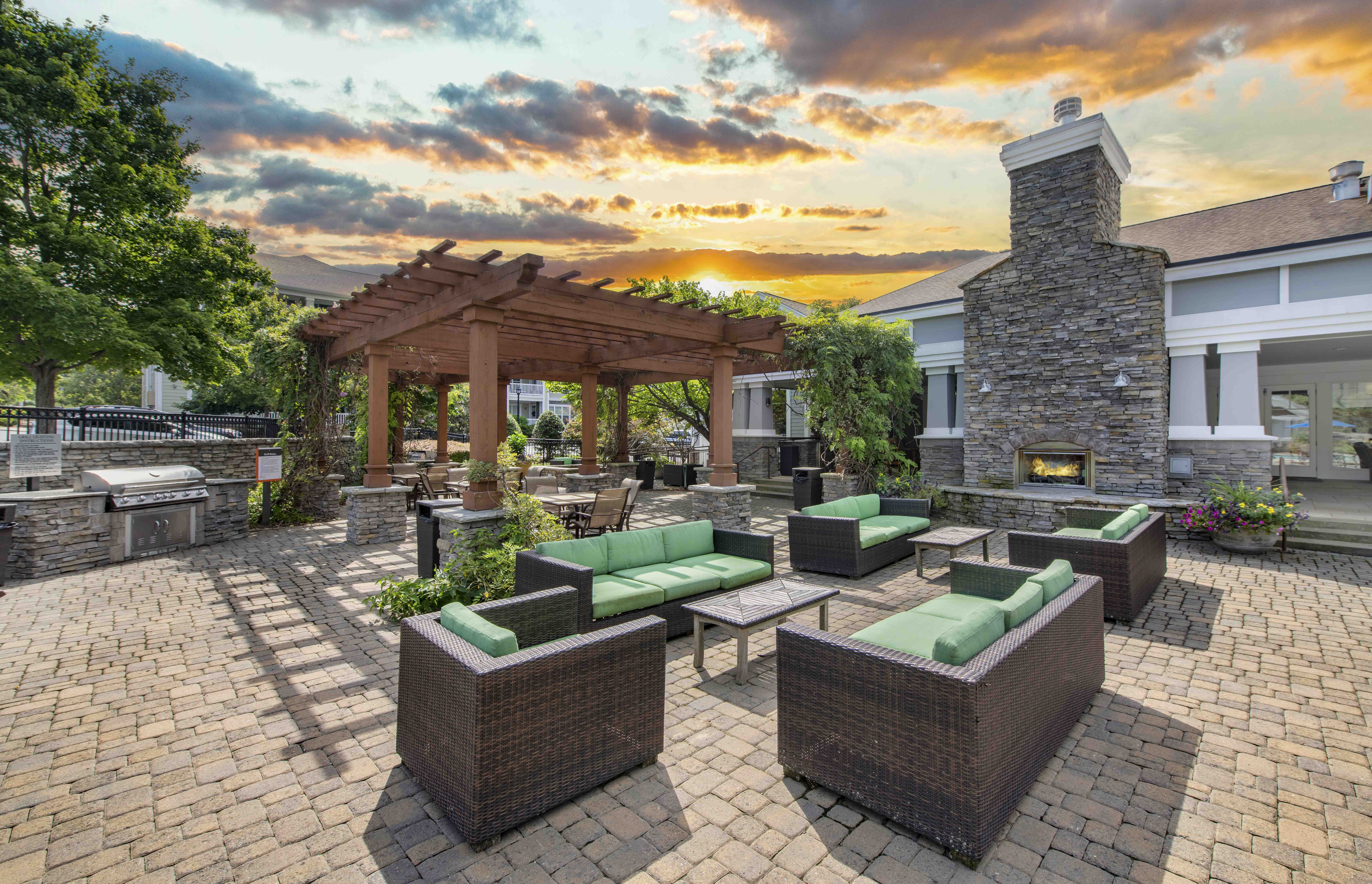 a patio with furniture and a pergola at sunset