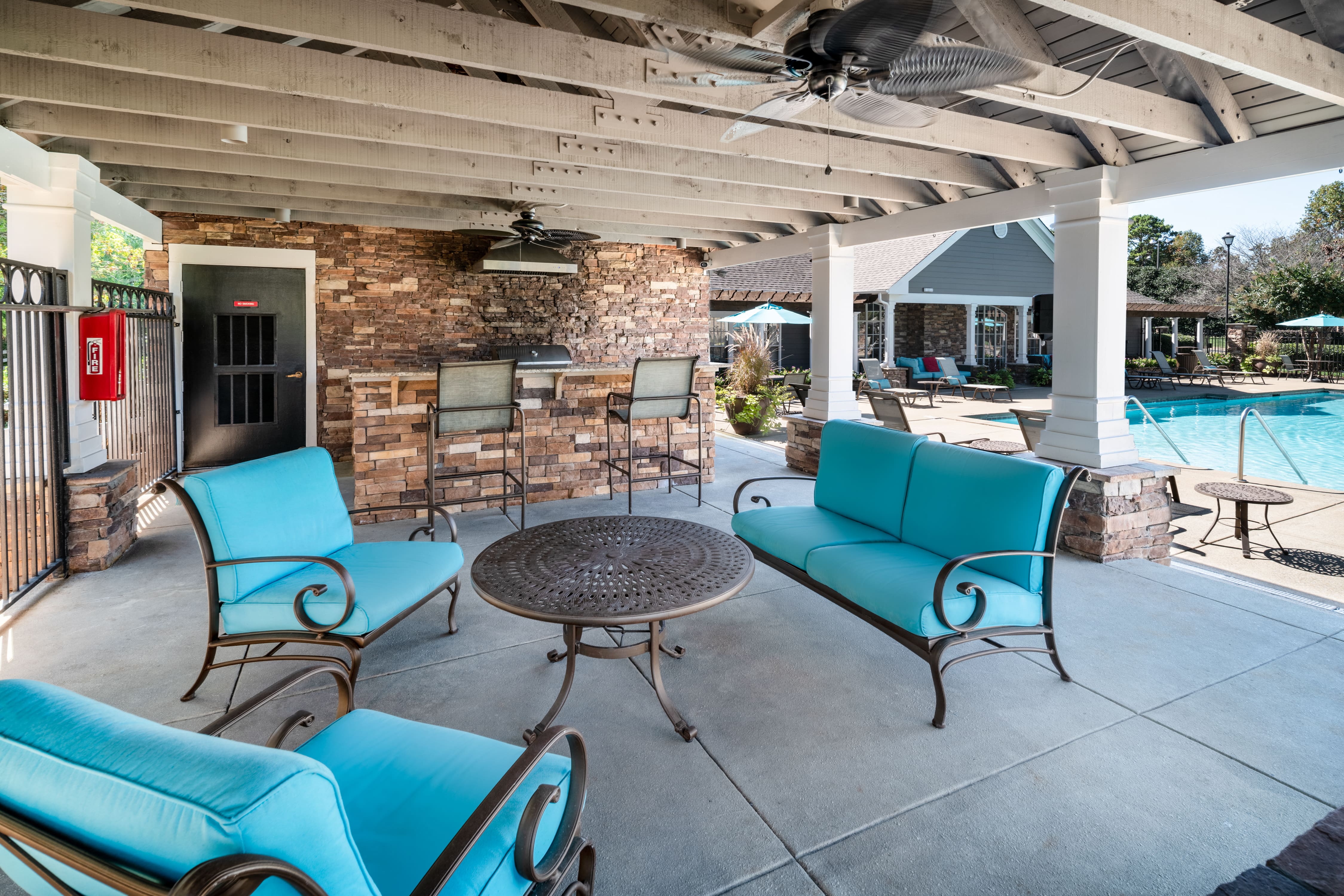 a covered patio with blue chairs and a table