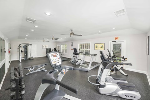 A gym with a variety of equipment including treadmills, elliptical machines, and weights.