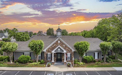 A house with a front yard and a parking lot in front.
