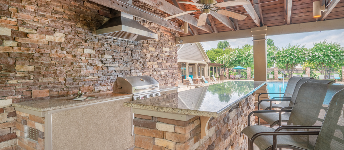 a large outdoor kitchen with a grill and a pool