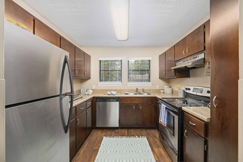 A kitchen with a refrigerator on the left and a sink in the middle.