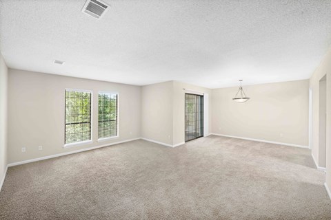 A spacious room with carpeted floor and sliding glass doors.