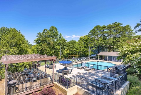 A pool area with a table and chairs under a pergola.