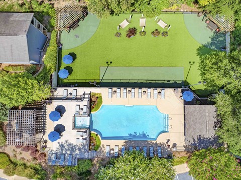 A large swimming pool surrounded by a grassy area and trees.