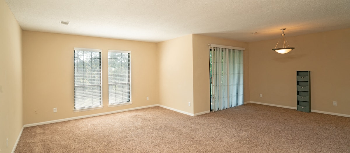 an empty living room with windows and a door to a closet