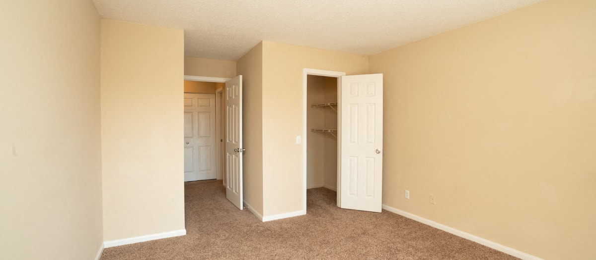 an empty bedroom with a closet and an open door