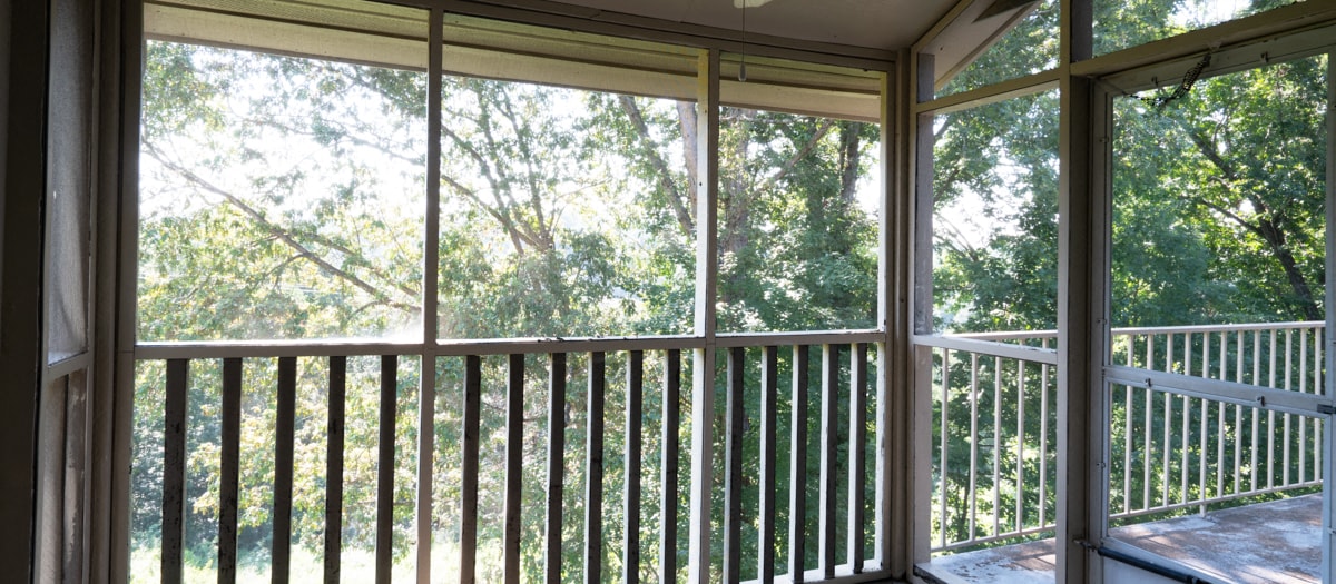 a screened in porch with a view of the trees