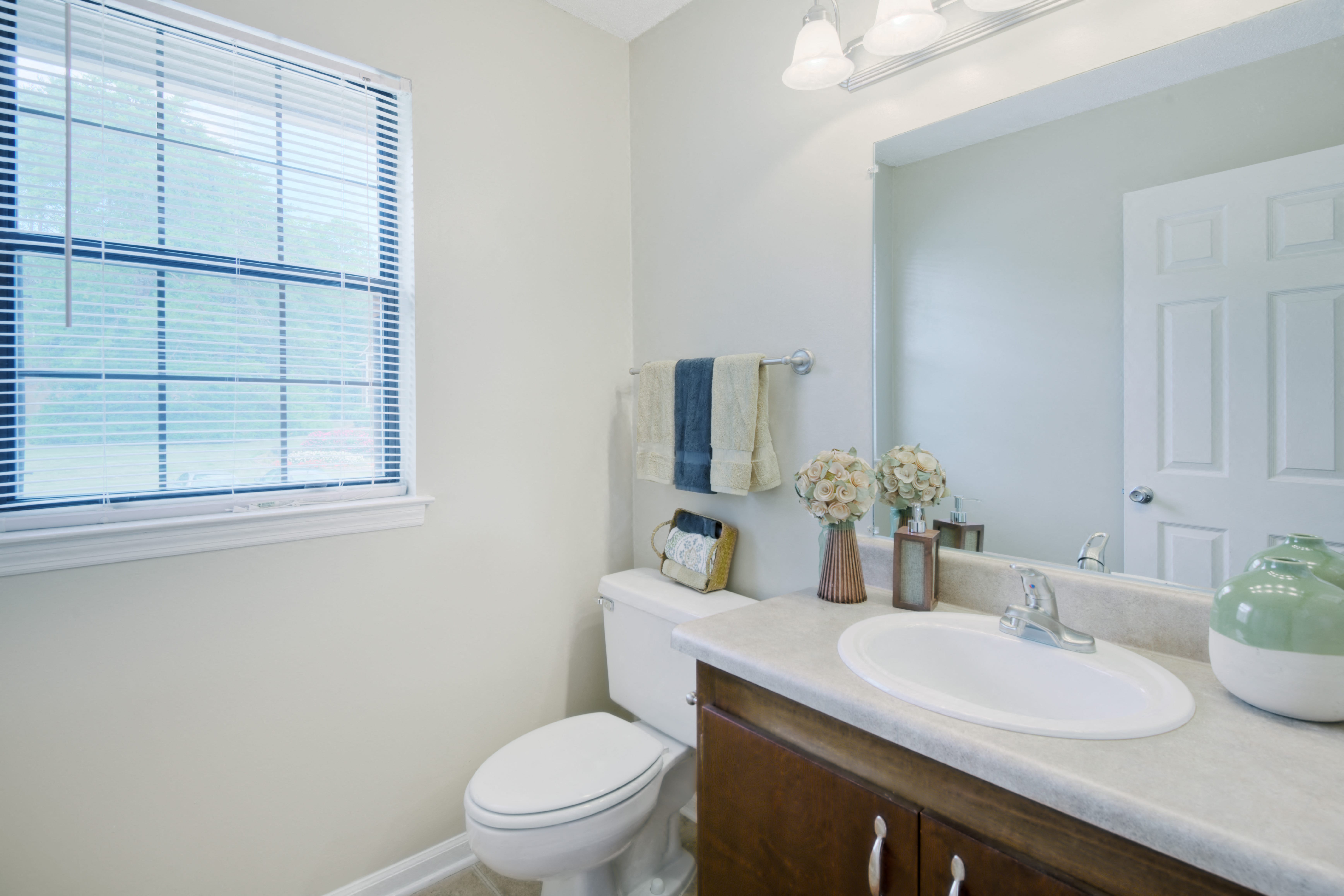 a bathroom with a toilet sink and mirror and a window