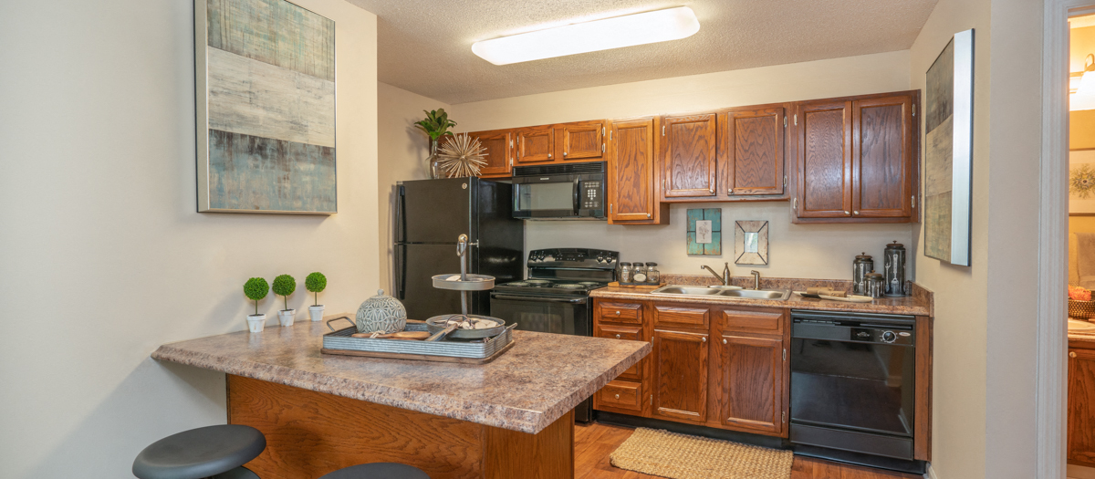 a kitchen with black appliances and wooden cabinets and a granite counter top
