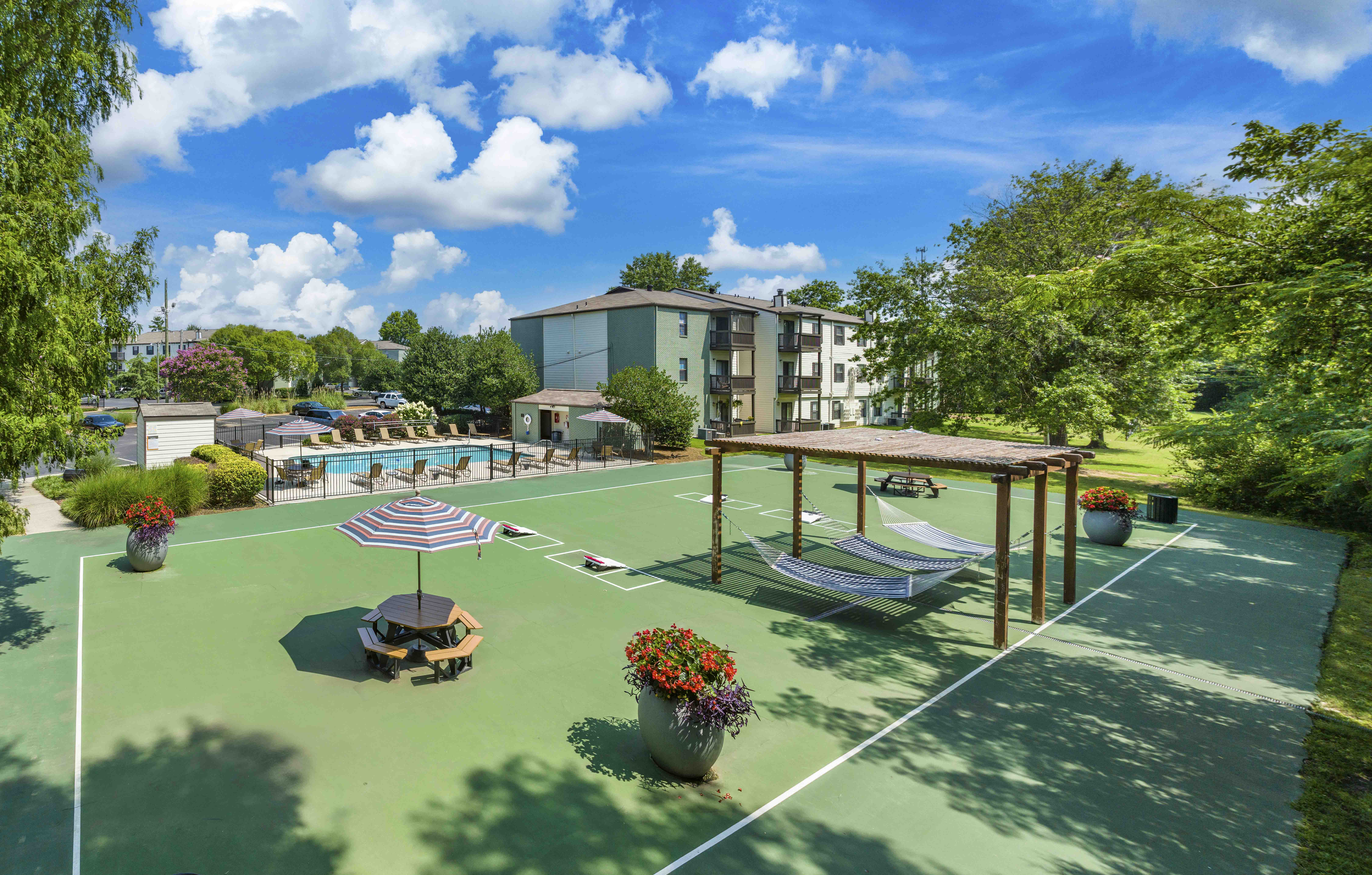 a tennis court with lounge chairs and an umbrella on it