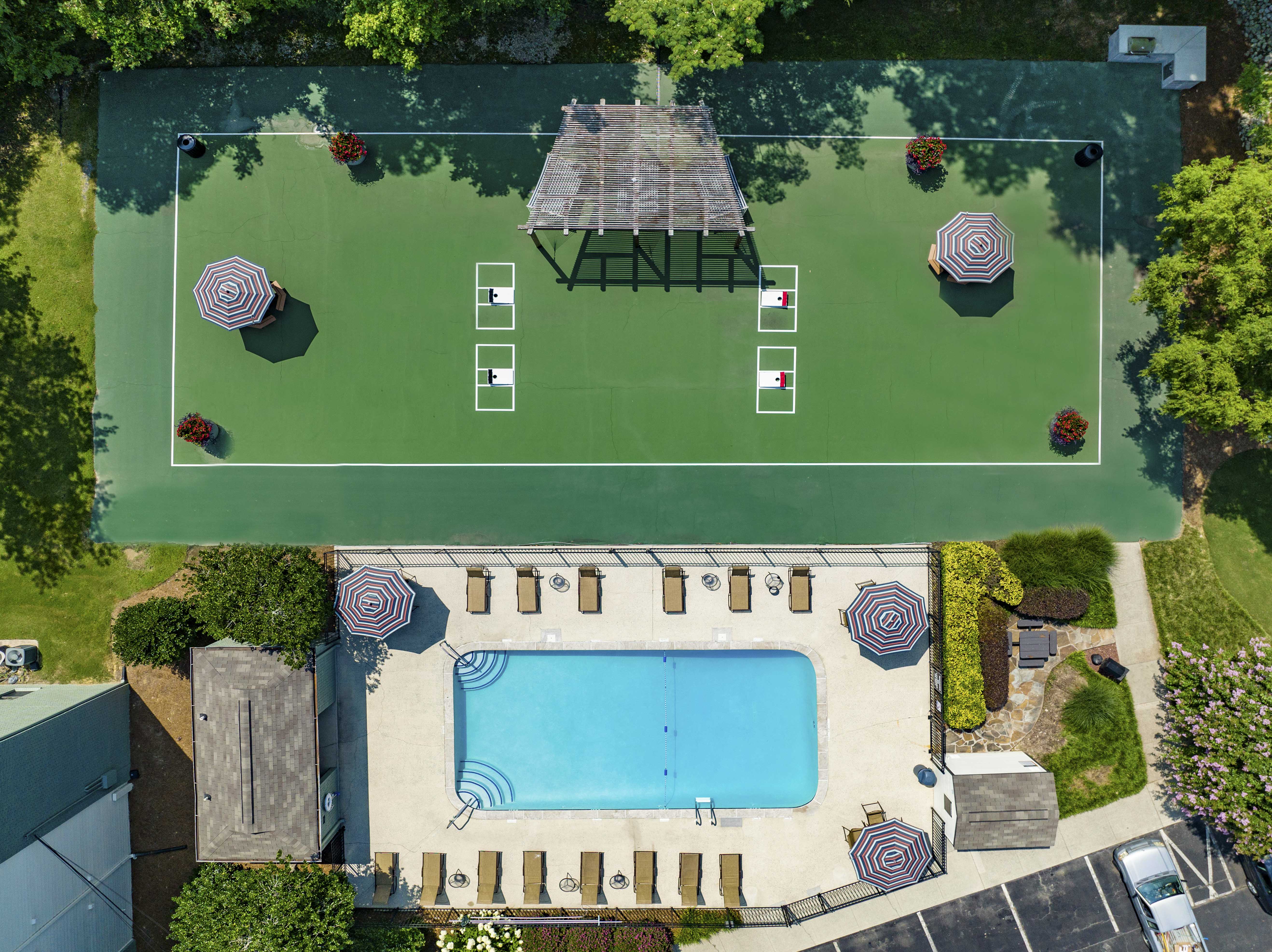 arial view of a tennis court with a pool and umbrellas