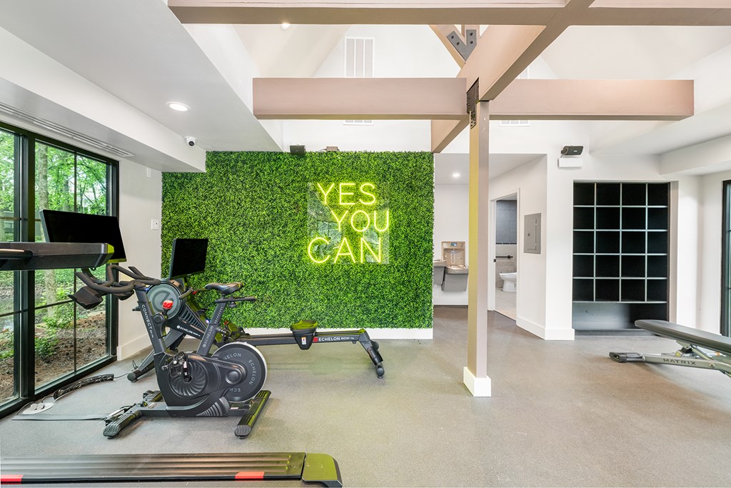 A room with a green wall that says "YES YOU CAN" and exercise equipment.