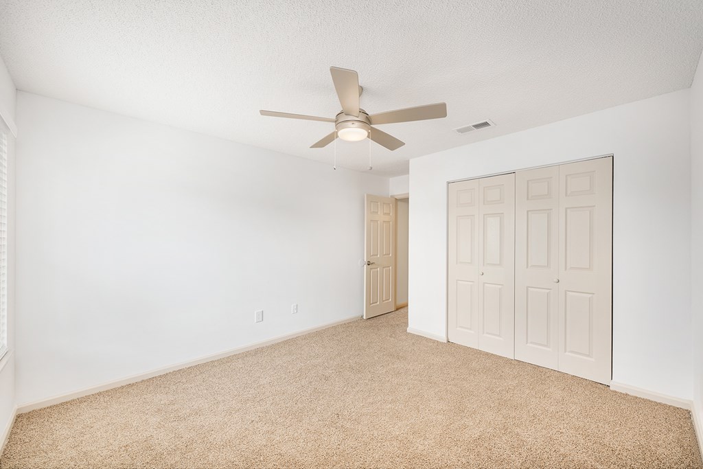 A room with a ceiling fan and carpeted floor.