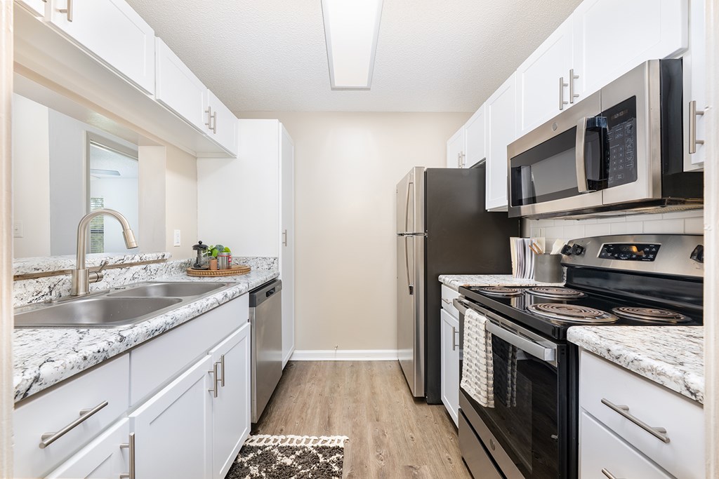 A kitchen with white cabinets and a black refrigerator.