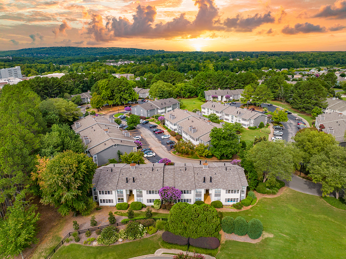an aerial view of a group of houses with a sunset in the background