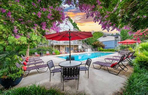 a swimming pool with patio furniture and a red umbrella