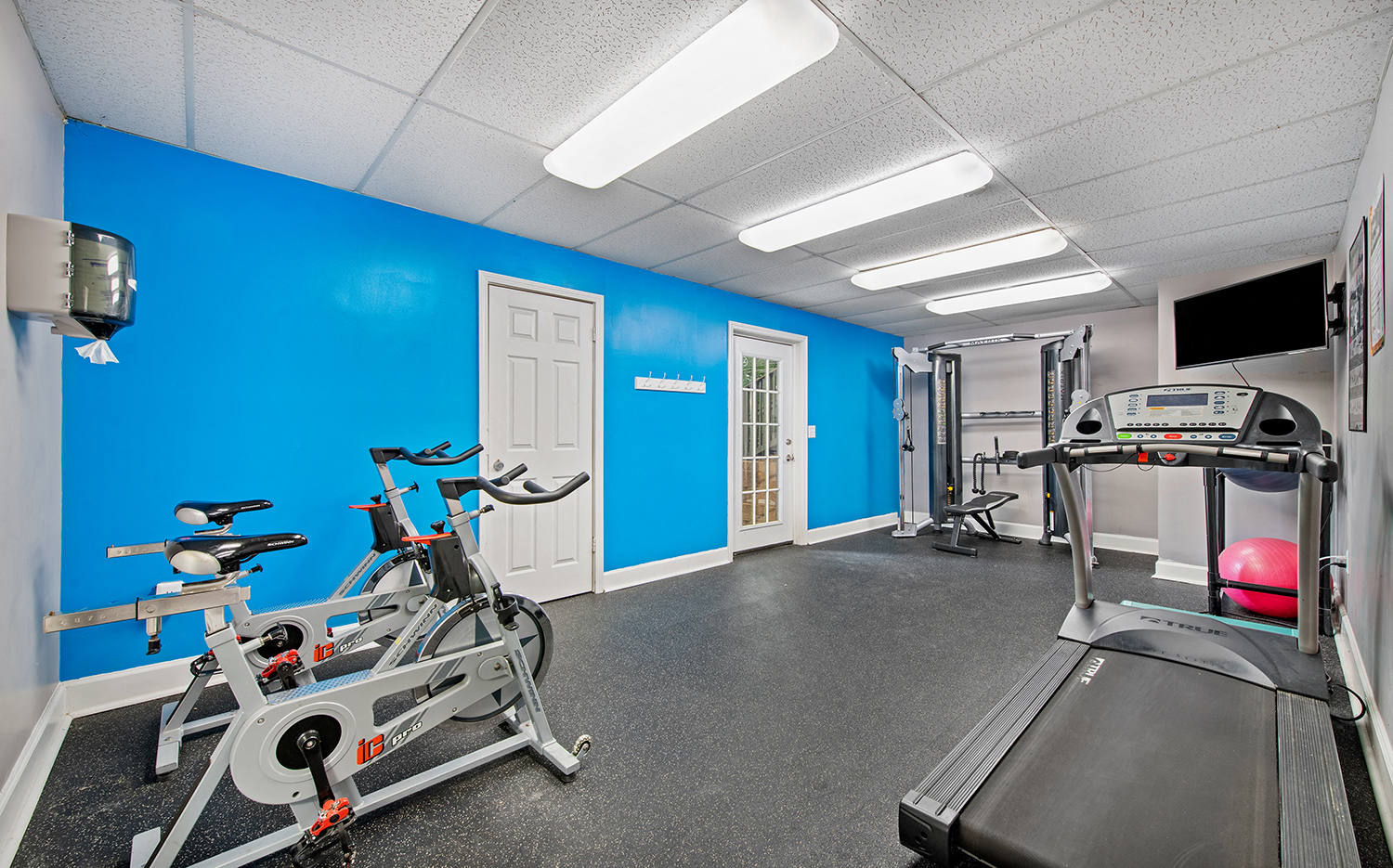 a gym with exercise equipment and a blue wall