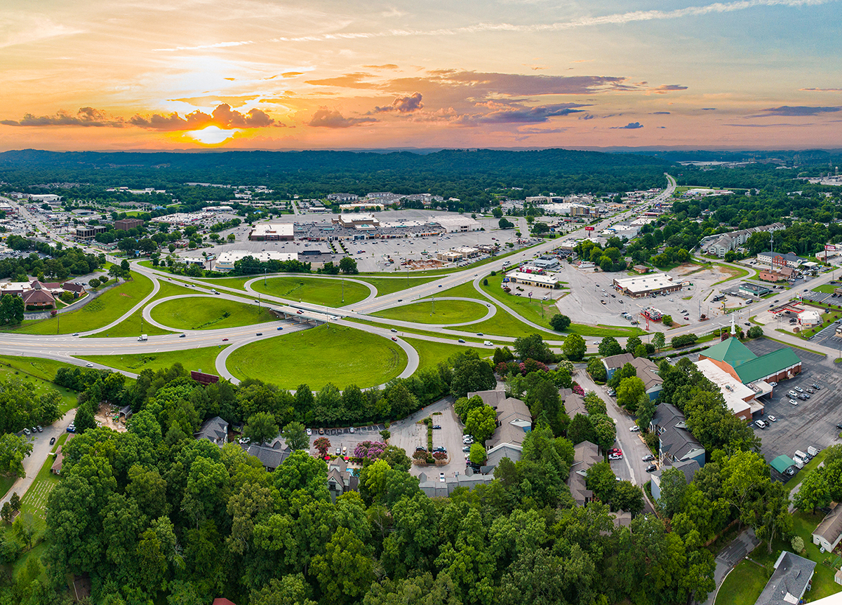an aerial view of a city at sunset with highways and trees