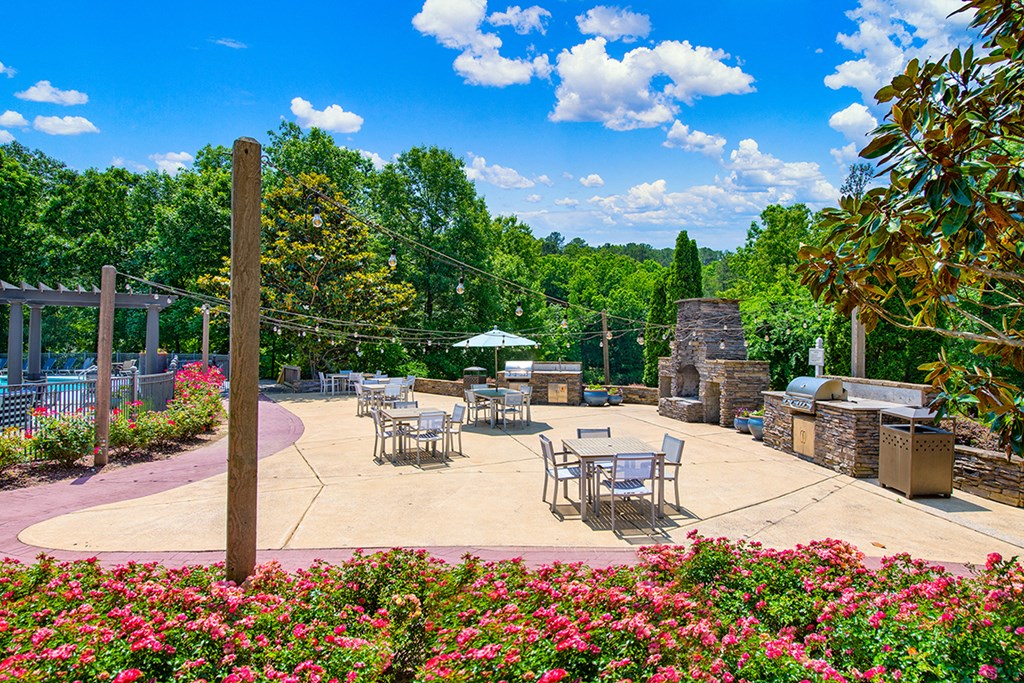 an outdoor patio with tables and chairs and a grill