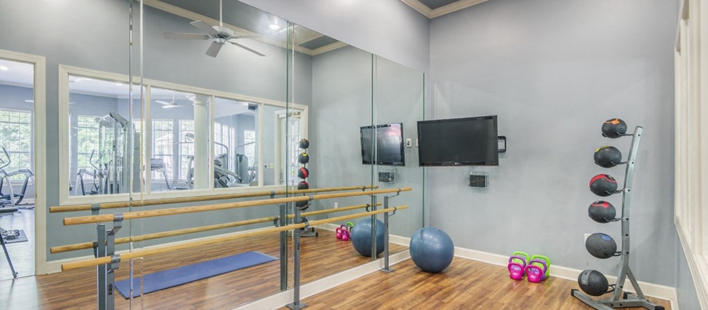 a gym with a reformer and weights and a television on the wall