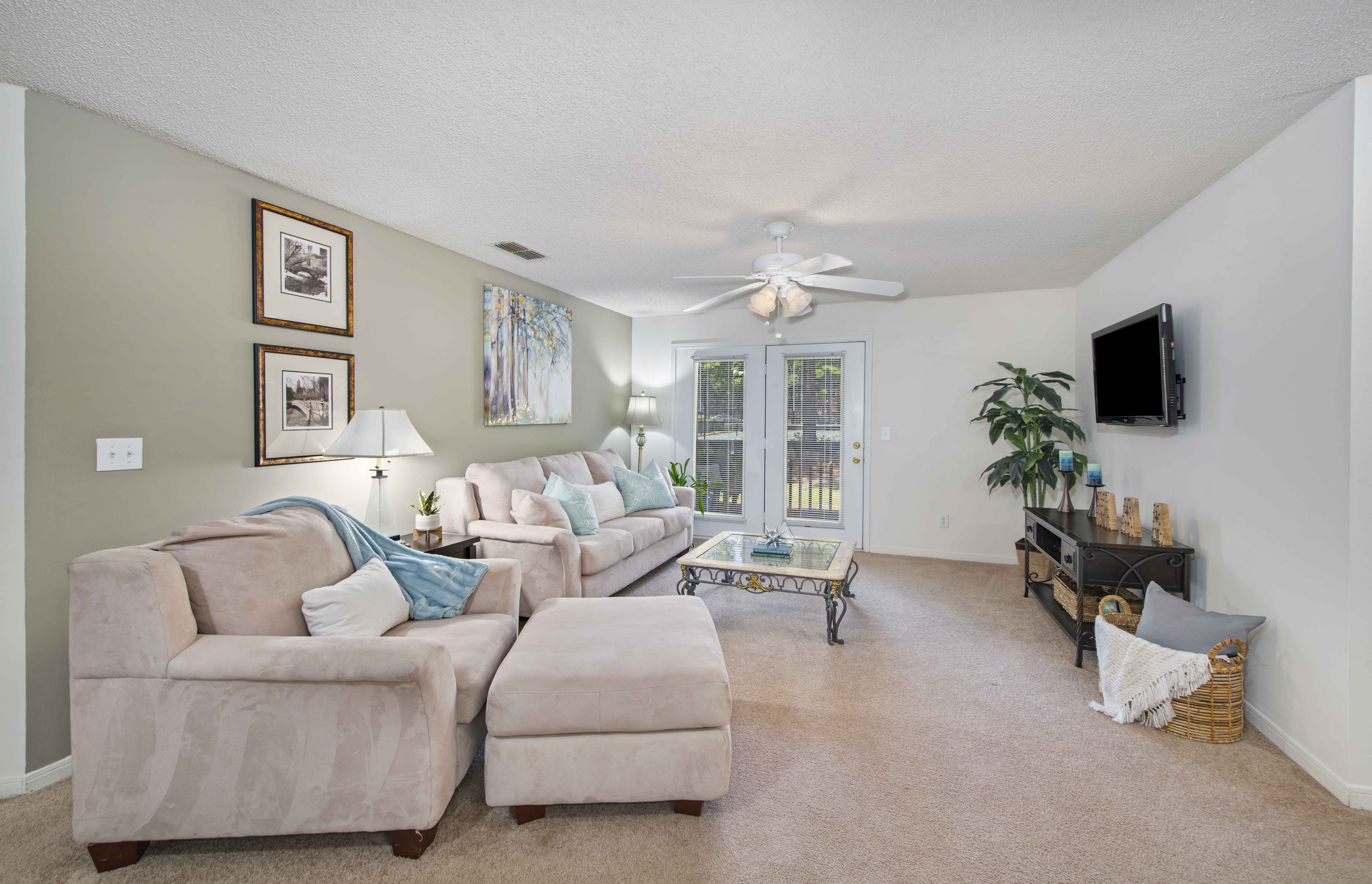 a living room with a couch and a chair and a ceiling fan