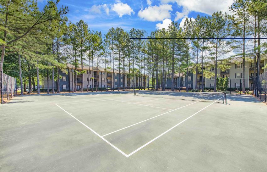 a tennis court with trees and apartments in the background