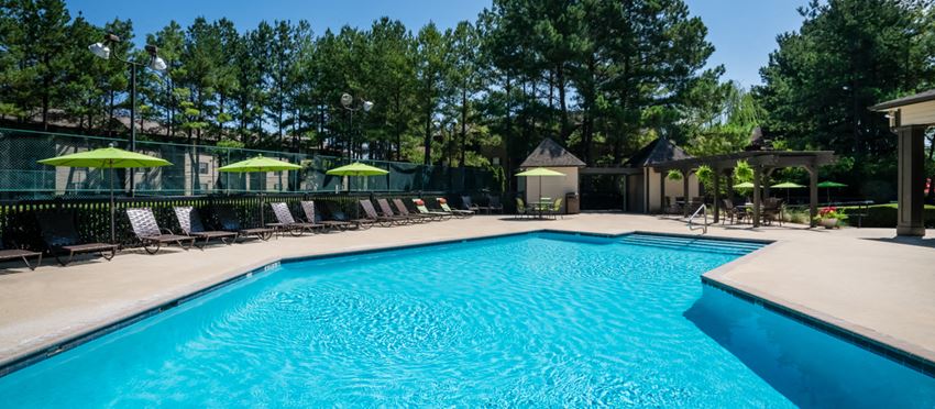 a swimming pool with chairs and umbrellas next to a resort style pool