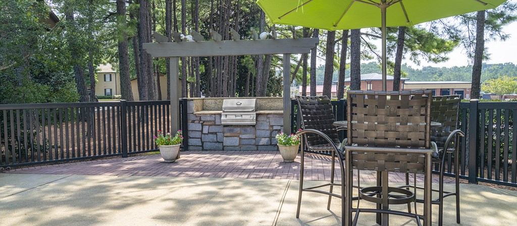 a patio with chairs and a grill and an umbrella