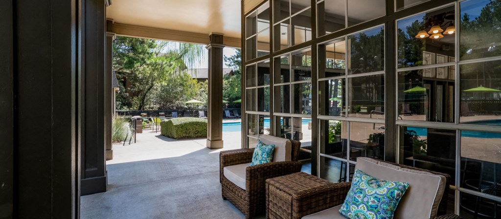 a patio with wicker furniture and large glass windows