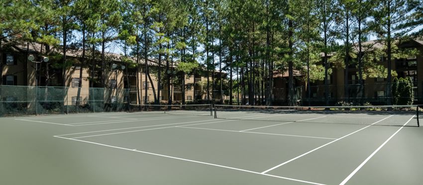 a tennis court in front of a building with trees