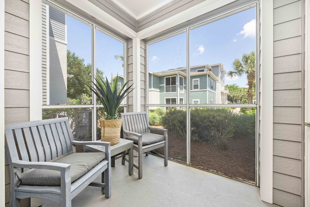 A patio with two chairs and a table with a potted plant on it.