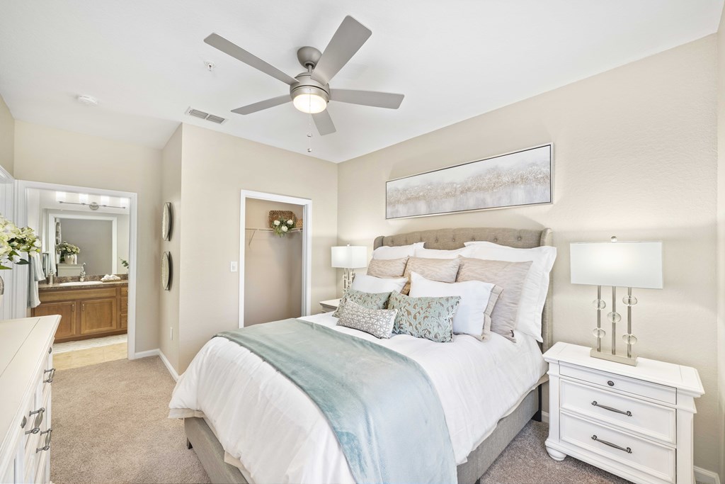 A bedroom with a bed, nightstand, and a ceiling fan.