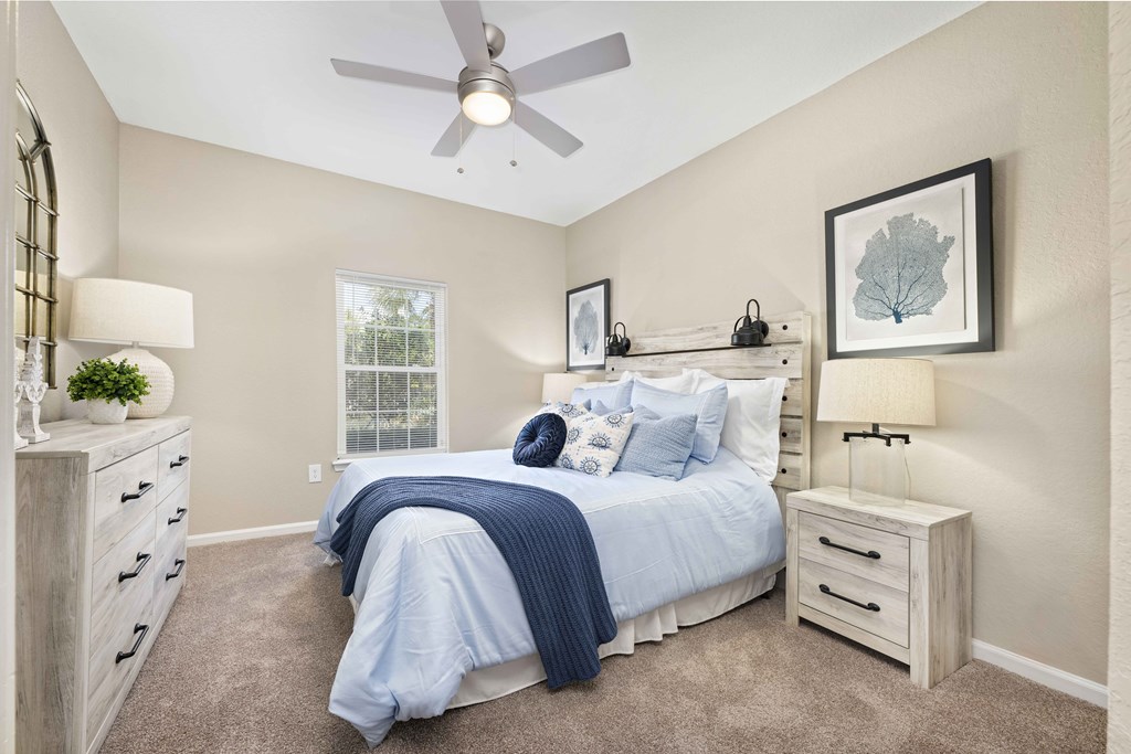 A bedroom with a bed, nightstands, and a ceiling fan.