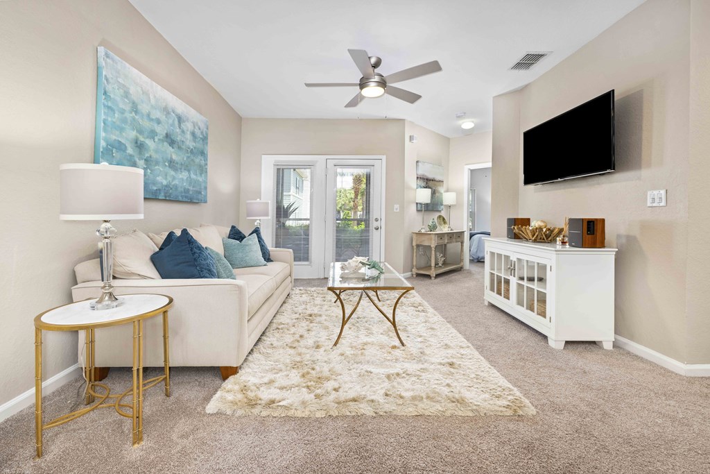 A living room with a white couch, a gold side table, and a large painting on the wall.