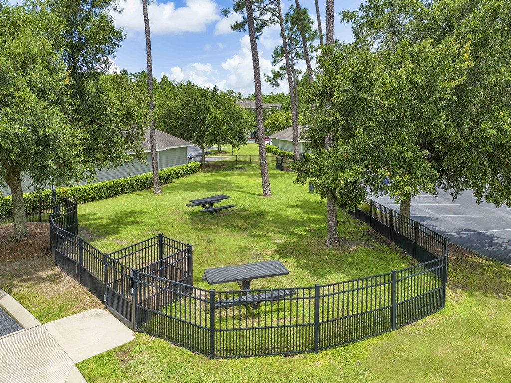 A black fence surrounds a green lawn with a picnic table.
