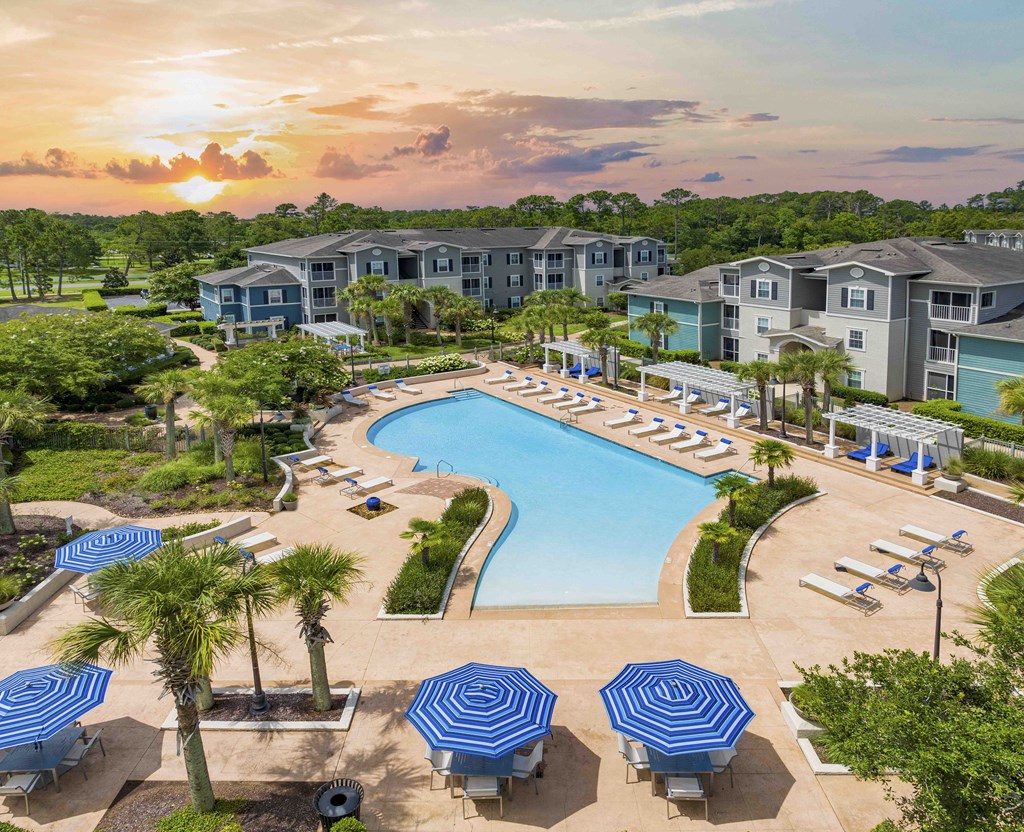 A sunset view of a resort with a pool and loungers.