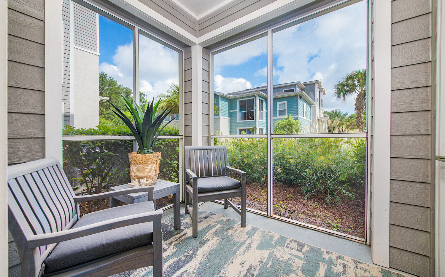 a screened in porch with two chairs and a potted plant