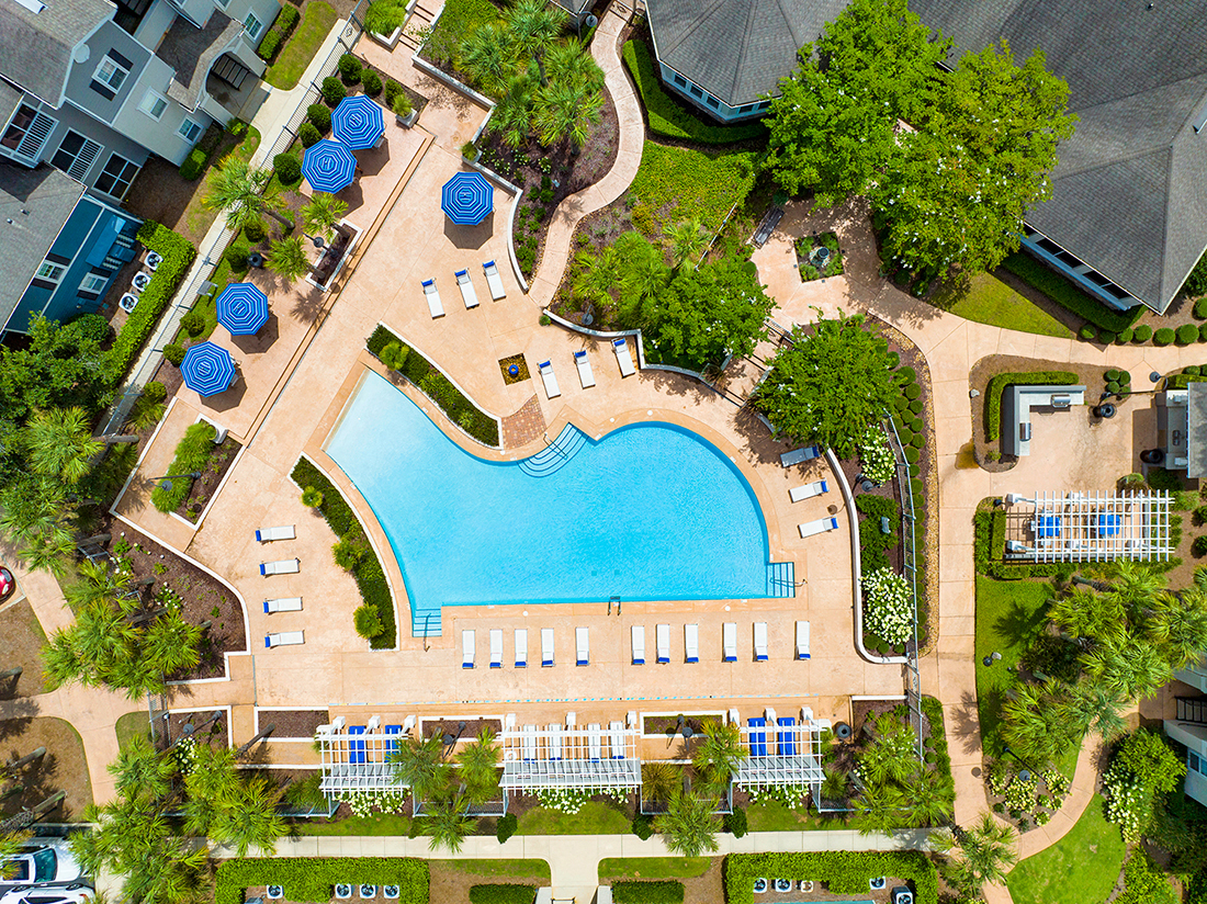 an overhead view of a swimming pool with umbrellas and trees