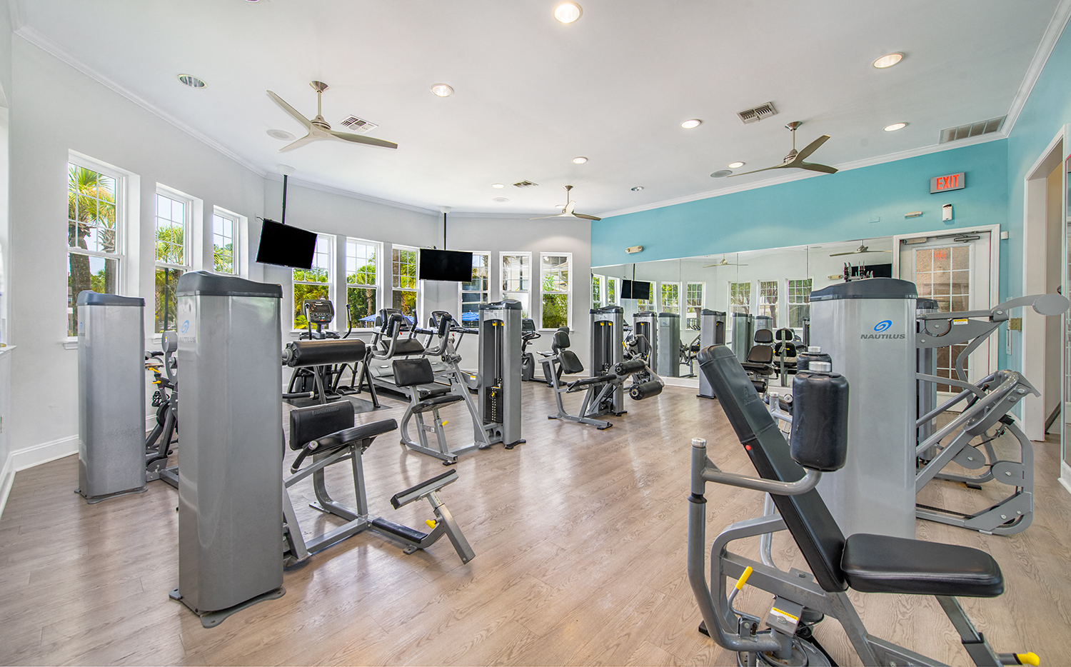 a fitness center with cardio equipment and weights in a building with windows