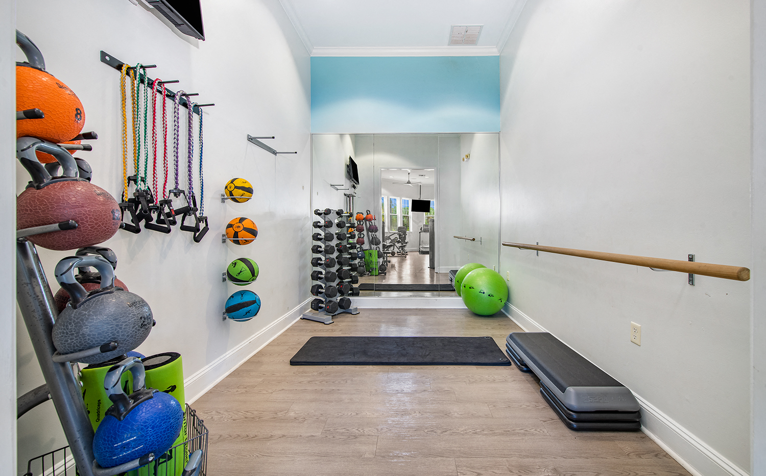 a workout room with weights and racks of dumbbells on the wall
