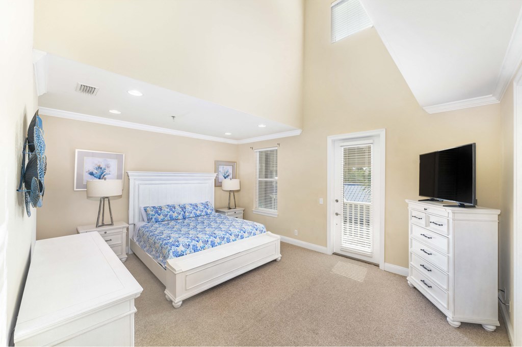 A bedroom with a white bed, dresser, and nightstand.