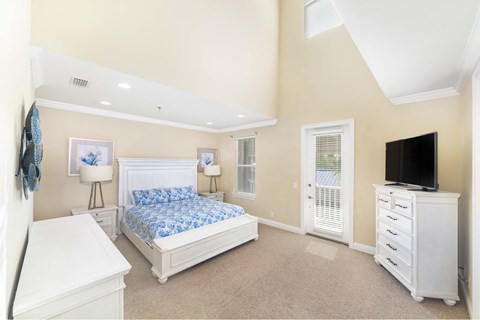 A bedroom with a white bed, dresser, and nightstand.