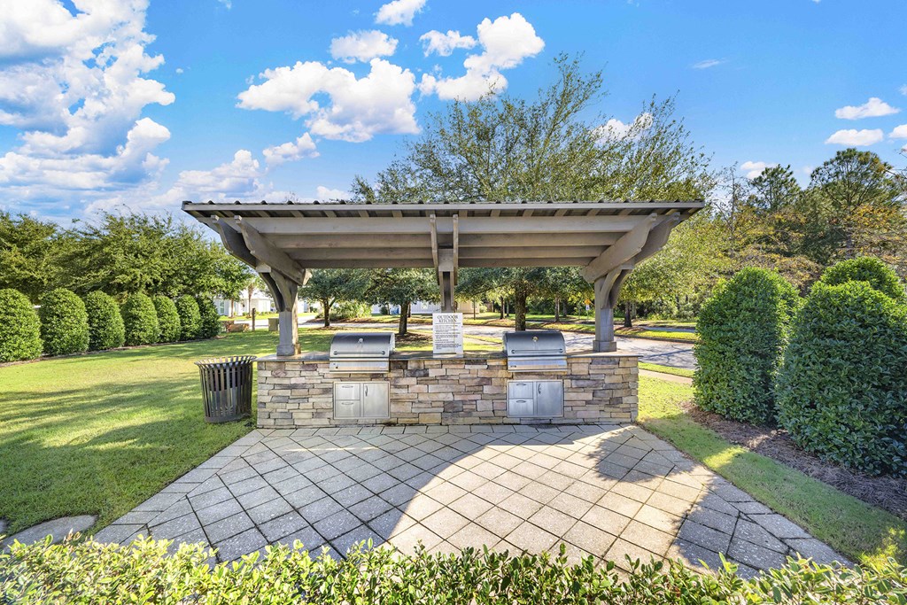 A pavilion with a stone base is surrounded by greenery.