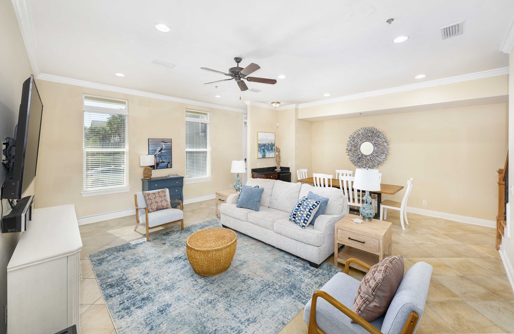 A living room with a white couch, a blue rug, and a ceiling fan.